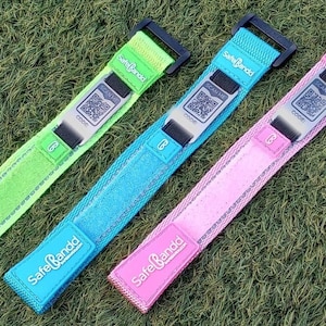 May include: Three colourful wristbands with the text "Safe Bandd" printed on them. The wristbands are green, blue and pink.