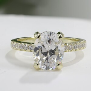 Op de afbeelding: Een gouden verlovingsring met een grote ovale diamant als middelste steen en een band met kleinere diamanten.