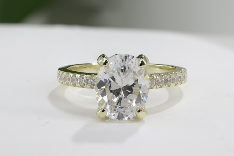 Op de afbeelding: Een gouden verlovingsring met een grote ovale diamant als middelste steen en een band met kleinere diamanten.