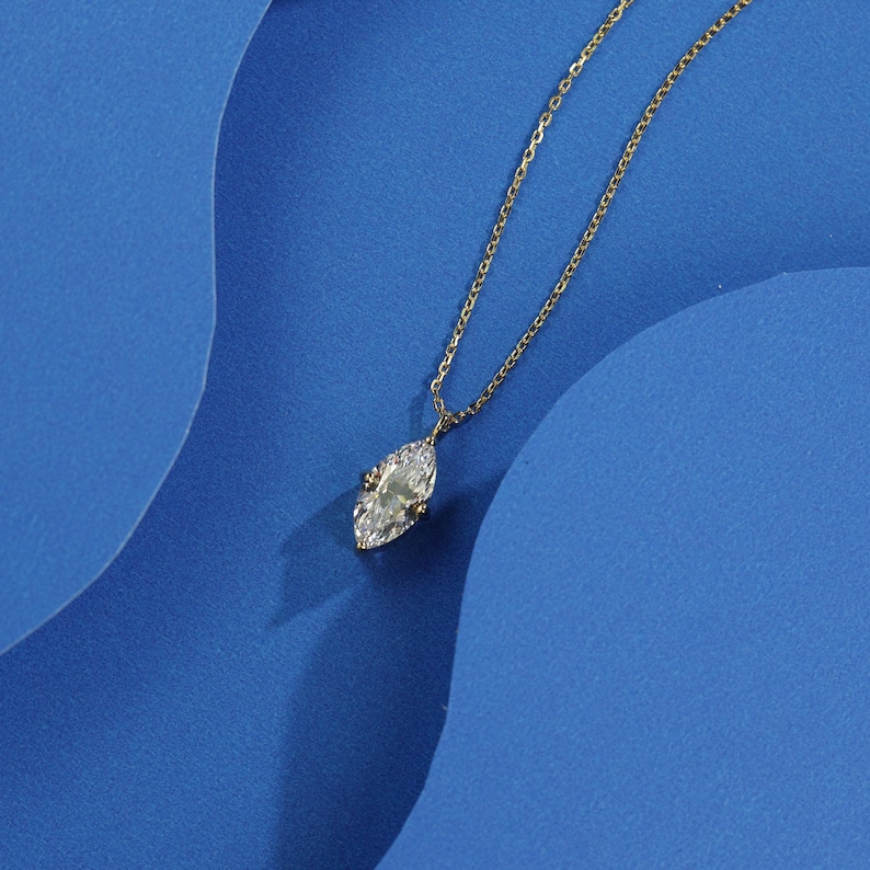 May include: A gold chain necklace with a clear marquise-shaped pendant.