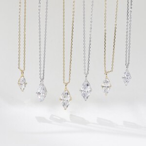 May include: Six delicate necklaces with marquise-shaped diamond pendants. The necklaces are on a white background and feature both gold and silver chains.