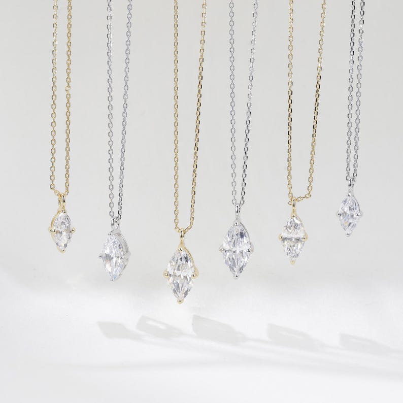 May include: Six delicate necklaces with marquise-shaped diamond pendants. The necklaces are on a white background and feature both gold and silver chains.