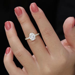 Op de afbeelding: Een gouden verlovingsring met een ovale centrale diamant en een band met kleinere diamanten.