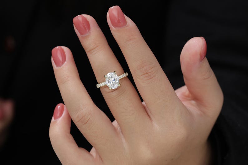 Op de afbeelding: Een gouden verlovingsring met een ovale centrale diamant en een band met kleinere diamanten.