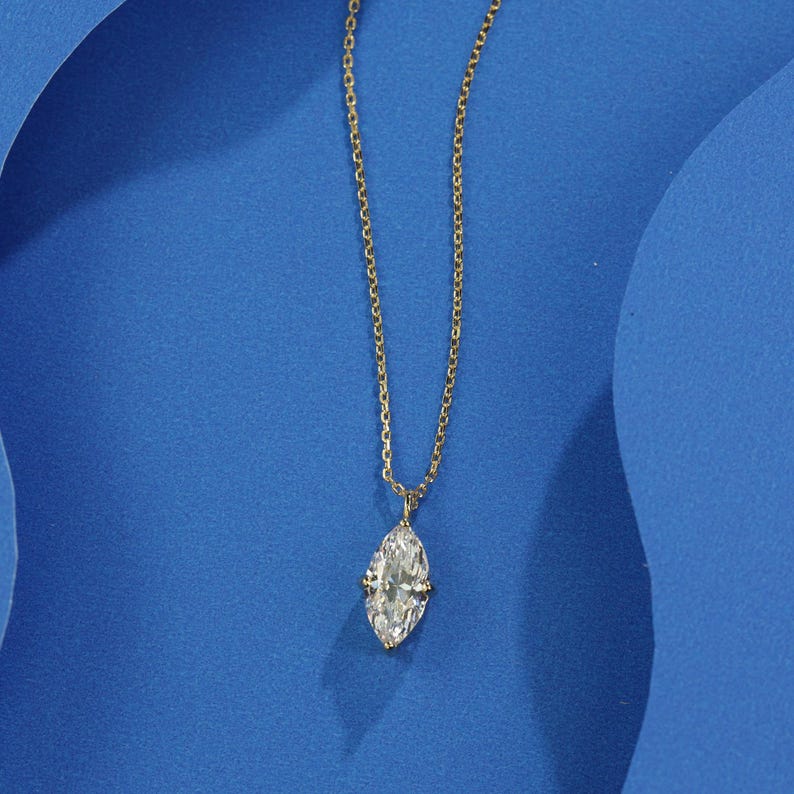 May include: A gold chain necklace with a marquise-shaped diamond pendant.