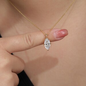 May include: A gold chain necklace with a marquise-shaped diamond pendant.