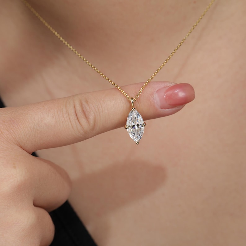 May include: A gold chain necklace with a marquise-shaped diamond pendant.