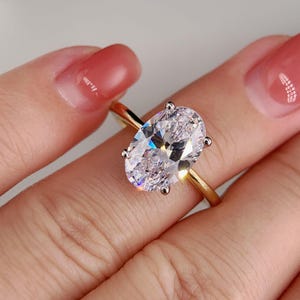 May include: A gold ring with a large oval-shaped diamond. The diamond is clear and sparkly.