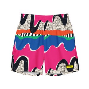 May include: Vibrant swim shorts with a colorful abstract design. The shorts feature a pink base with blue, green, orange, and black wavy patterns, and a dotted white background. The waistband is pink. The shorts have a small yellow tag with text.