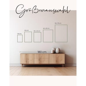 May include: A display of framed art prints in various sizes, including DIN A4, DIN A3, 30 x 40 cm, 40 x 50 cm, and 50 x 70 cm. The text "Gr&ouml;&szlig;enauswahl" is at the top. A wooden cabinet, 180 cm long, is below the frames.
