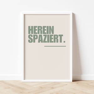 Könnte beinhalten: Ein weißer gerahmter Druck mit dem Text "HEREIN SPAZIERT." in Grün auf beigefarbenem Hintergrund.