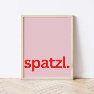 Può includere: Una stampa incorniciata con uno sfondo rosa e la parola "spatzl." in lettere rosse.