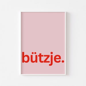Könnte beinhalten: Ein rosa Poster mit dem Wort "bützje" in roten Buchstaben.