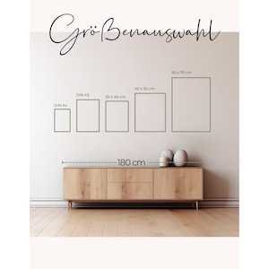 May include: A display of framed art prints in various sizes, including DIN A4, DIN A3, 30 x 40 cm, 40 x 50 cm, and 50 x 70 cm, against a white wall. A wooden cabinet, approximately 71 inches long, sits below the frames. The text "Gr&ouml;&szlig;enauswahl" is at the top.