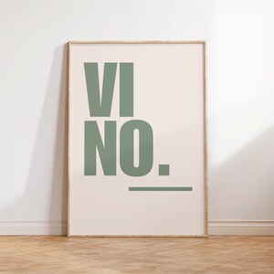 Op de afbeelding: Ingelijste kunstdruk met het woord "VINO" in grote, saliegroene blokletters op een crèmekleurige achtergrond. Het woord "NO." staat onder "VI" met een horizontale lijn eronder. De lijst heeft een lichte houtkleur.