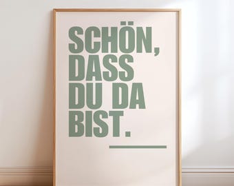 Può includere: Una stampa da parete rettangolare in una cornice di legno chiaro con il testo tedesco "SCHÖN, DASS DU DA BIST." in lettere maiuscole color verde salvia su sfondo crema chiaro, con una linea orizzontale verde salvia sotto il testo.