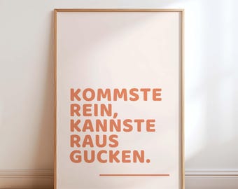Può includere: Una stampa artistica incorniciata con la frase tedesca "KOMMSTE REIN, KANNSTE RAUS GUCKEN" in lettere arancioni su sfondo color pesca chiaro. La stampa è in una cornice di legno naturale ed è esposta contro un muro bianco.
