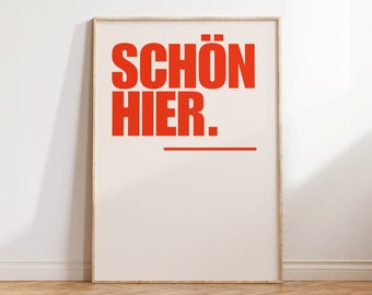 Puede incluir: Una impresión enmarcada con el texto "SCHÖN HIER." en letras rojas y negritas sobre un fondo blanco.