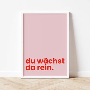 Könnte beinhalten: Ein gerahmter Druck mit hellrosa Hintergrund und rotem Text, der "du wächst da rein." lautet.