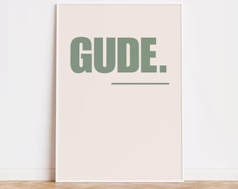 Puede incluir: Un póster enmarcado blanco con la palabra "GUD.E." impresa en verde claro sobre un fondo crema.