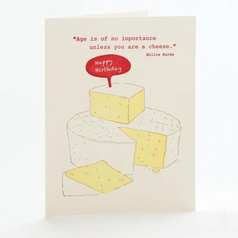 Może przedstawiać: Kremowa kartka urodzinowa z ilustracją o tematyce serowej. Karta zawiera cytat i czerwony dymek z napisem "Happy Birthday". Ilustracja przedstawia stos blok&oacute;w sera i klin.