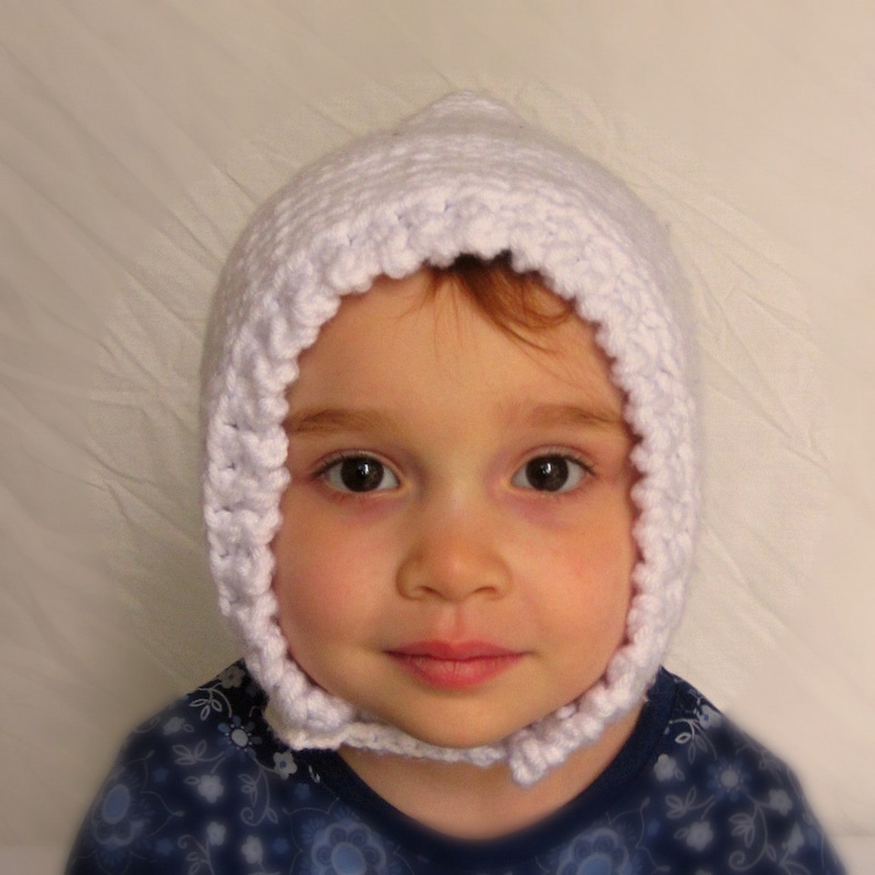Peut inclure: Un bonnet de b&eacute;b&eacute; en crochet blanc avec un bord festonn&eacute;. Le bonnet est port&eacute; par un b&eacute;b&eacute; aux cheveux bruns et aux yeux bruns.
