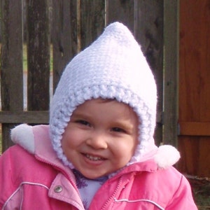 May include: A young child wearing a white crocheted hat with ear flaps and a pink winter jacket.