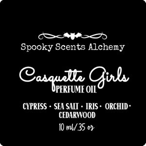 May include: Black and white label with the text "Spooky Scents Alchemy" and "Casquette Girls Perfume Oil" with a bat graphic. The label lists the fragrance notes: Cypress, Sea Salt, Iris, Orchid, Cedarwood. The label also states the volume: 10 ml / .35 oz.