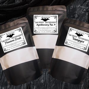 May include: Three matte black stand-up pouches containing laundry detergent. Each pouch features a white rectangular label with a black bat graphic and text reading Laundry Detergent, followed by the names Phantom Fresh, Apothecary No. 9, or Vampyre.