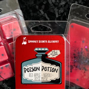 May include: A red and black soy blend melt with the text "Poison Potion" and "Red Apple + Neroli + Rose Musk". The label reads "Spooky Scents Alchemy", "Do Not Drink", and "Hand Poured In". The product is 2.8 ounces.