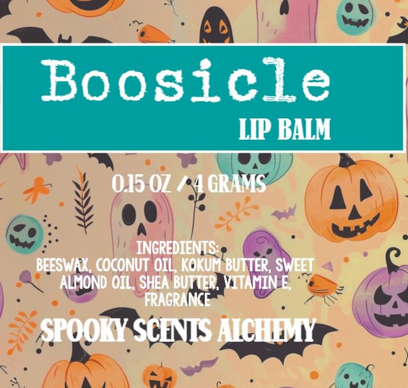 May include: A teal-colored label with the text "Boosicle LIP BALM" is set against a Halloween-themed background. The label also includes the size, ingredients, and the brand name "Spooky Scents Alchemy". The background features pumpkins, ghosts, and bats.