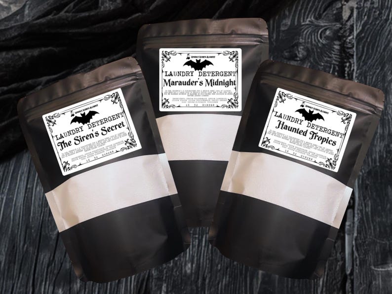 May include: Three matte black stand-up pouches containing laundry detergent. Each pouch features a white rectangular label with a black bat graphic and text reading Laundry Detergent, The Siren's Secret, Marauder's Midnight, or Haunted Tropics.
