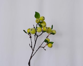 May include: A decorative branch featuring several green apples with a yellow hue and small green leaves. The apples are clustered along dark brown branches, creating a natural and rustic aesthetic. Perfect for home decor.