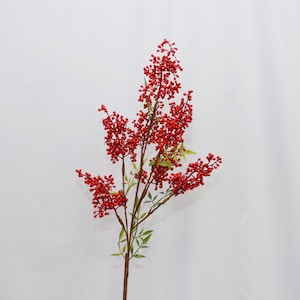 May include: An artificial stem with clusters of small, bright red berries. The berries are densely packed along the branches, which have a natural brown colour. Small green leaves are interspersed among the berries, creating a vibrant contrast.
