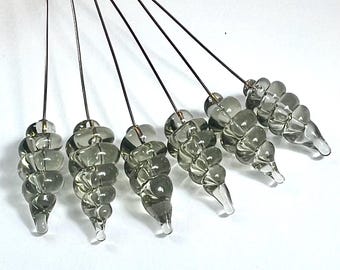 Könnte beinhalten: Sechs graue Glasperlen an dünnen Metalldrähten. Jede Perle ist eine Spirale aus kleinen, abgerundeten Glasstücken.