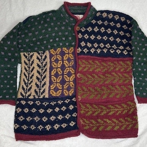 May include: A colourful patchwork cardigan. The sweater features a mix of patterns, including dots, diamonds, and floral motifs, in green, navy, burgundy, and tan. It has a button-up front and ribbed collar and cuffs. The garment is made of a thick, warm material.