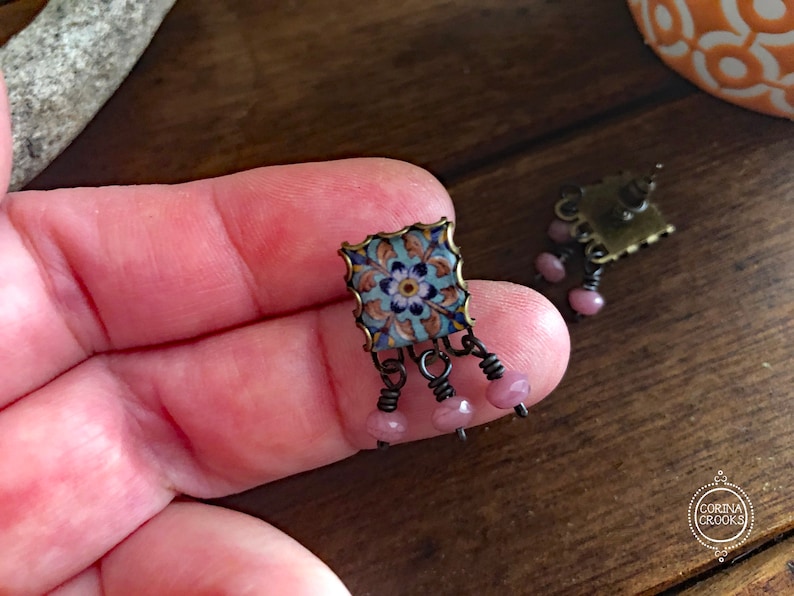 May include: A pair of earrings with a blue and white patterned tile design and pink beads hanging from the bottom.