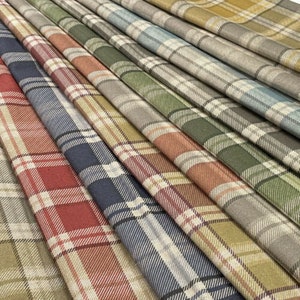 May include: A collection of plaid fabric swatches in various colors, including red, green, blue, and brown. The fabric has a woven texture and a classic plaid pattern.