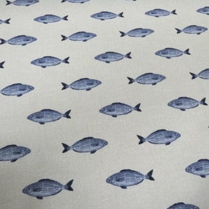 Puede incluir: Una tela blanca con un patrón repetitivo de peces azules. Los peces están todos mirando en la misma dirección y están espaciados uniformemente.