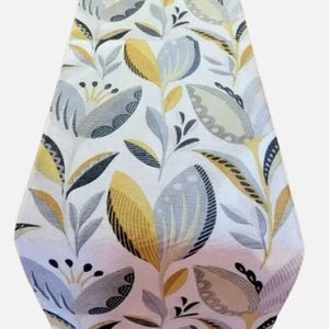 May include: A white table runner with a floral pattern in shades of grey, yellow, and black. The pattern features stylised leaves and flowers.