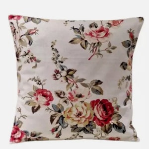 Könnte beinhalten: Ein weißes Kissen mit einem Blumenmuster mit rosa, roten und gelben Rosen. Das Kissen hat einen cremefarbenen Hintergrund und eine subtile Vintage-Atmosphäre.