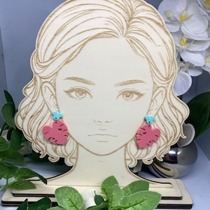 May include: A pair of pink and blue leaf-shaped earrings with a small blue butterfly charm hanging from each earring.