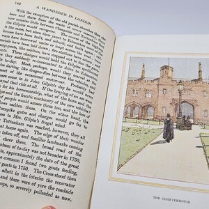 May include: An open book with text on the left page and a colour illustration on the right. The illustration shows a building with arched entryways, a lamppost, and a person walking on a path. The text below the illustration reads "THE CHARTERHOUSE."