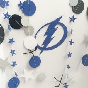 May include: A blue and white paper garland with stars, circles, and lightning bolts. The garland is perfect for a birthday party or other celebration.