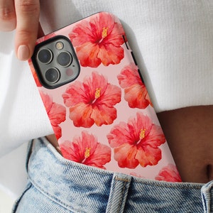 This phone case features a tropical collage pattern of red watercolour hibiscus flowers on a soft pink background. Perfect for coconut girls and beach lovers. Available for iPhone, Samsung and Pixel Phones.