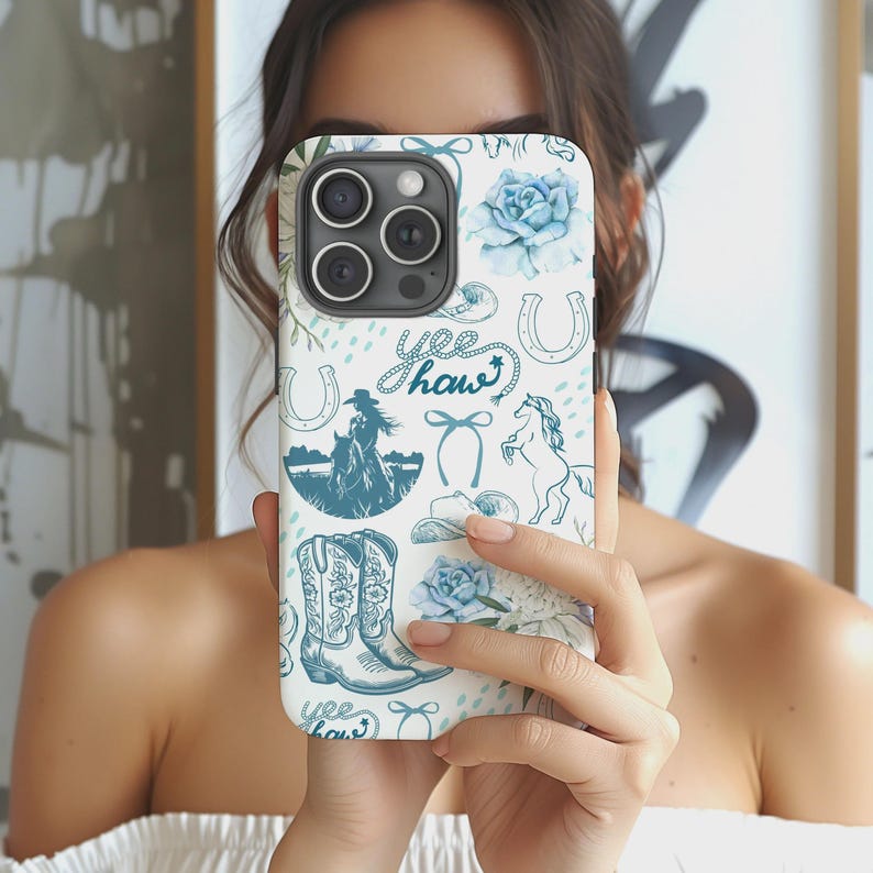 May include: A white iPhone case with a blue cowboy-themed pattern. The design includes horseshoes, cowboy boots, roses, a cowboy on a horse, and the words "Yee Haw". The case has a glossy finish and a camera cutout.