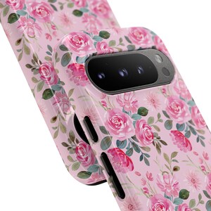 Pu&ograve; includere: Una custodia per telefono con sfondo rosa chiaro e un motivo ripetuto di rose rosa, fiori pi&ugrave; piccoli e foglie verdi tenui in stile acquerello. La custodia presenta un'area nera per la fotocamera e pulsanti laterali neri.