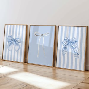 May include: Three framed prints with blue and white striped backgrounds and different blue bows. The bows are in various styles, including a simple bow, a large bow, and a checkered bow.