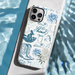 Coastal Coquette Cowgirl Phone Case. Featuring a collage of western inspired elements in shades of white and blue, mixed with some coquette style bows and flowers. The background is white and the colour palette is coastal and calm. For iPhone, Samsung & Pixel