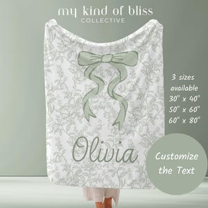 My Personalized Sage Green Bow Toile Name Blanket features a classic olive toile print with delicate flowers and birds on a crisp white background, topped with a big coquette-style bow and your custom name in an elegant script below. Soft feminine and beautifully detailed, it’s perfect for babies, kids, teens and adults. Great for sleepover favors, hospital or coming-home blankets, announcement photos, dorm rooms, teen bedrooms, Christmas, birthdays, sisters, newborn keepsakes and new parents